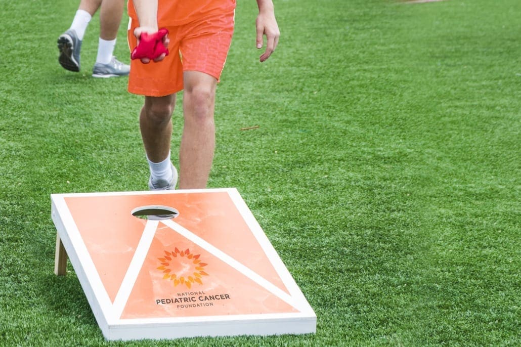 Boy standing behind a NPCF brand cord hole board ready to toss a bean bag