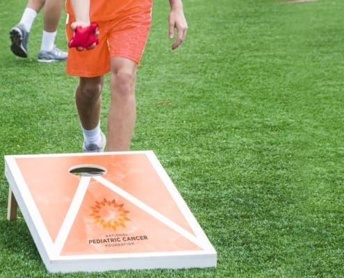 Boy standing behind a NPCF brand cord hole board ready to toss a bean bag
