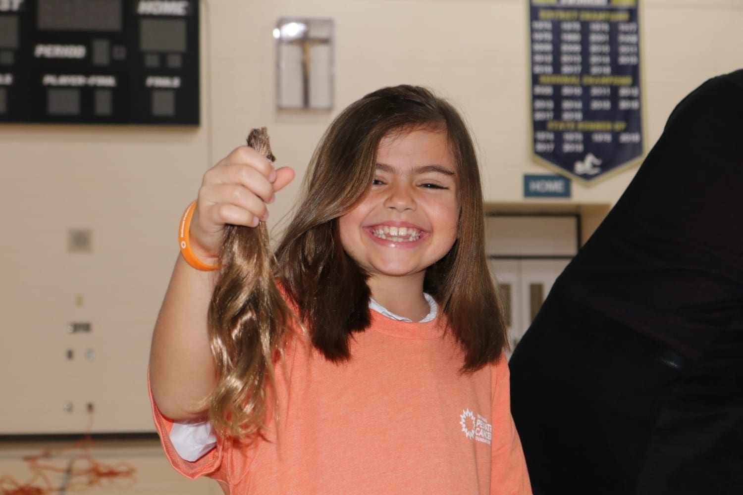 Young girl shows off her hair after it was cut off at the National Pediatric Cancer Foundation's Cut and Color Funds the Cure with the Academy of Holy Names in Tampa, Florida