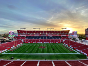A football stadium at sunset with empty seats and a well-maintained field.